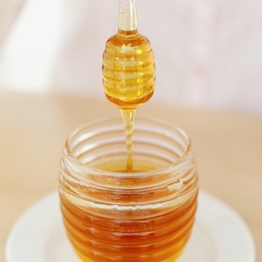 一罐蜂蜜上的蜂蜜勺子的特写